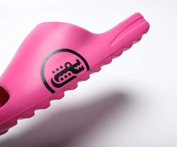 A pink toothbrush with black lettering on it.