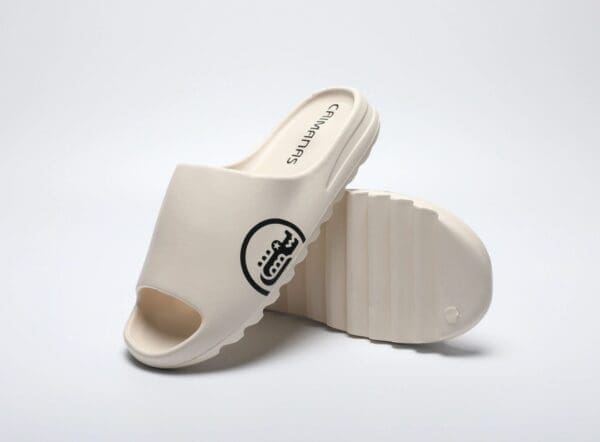 A pair of white sandals with a black logo.