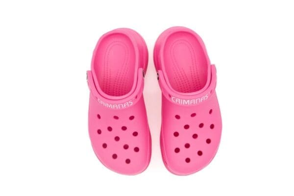 A pair of pink crocs are sitting on top of the floor.