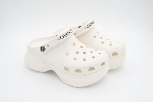 A pair of white crocs are on top of each other.