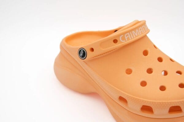 A close up of the strap on the bottom of an orange crocs shoe.