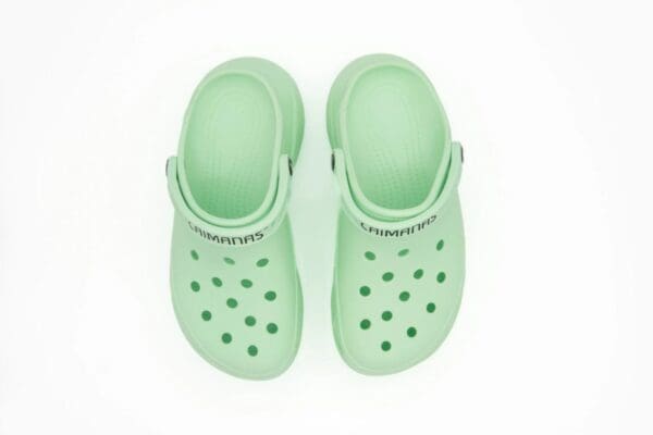 A pair of green crocs on top of each other.