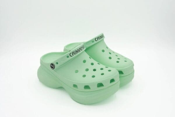 A pair of green crocs with the word crock on them.