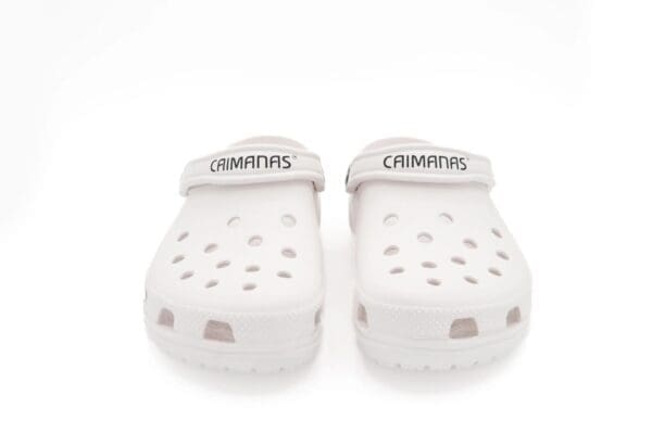 A pair of white crocs with the word " simmons " written on them.