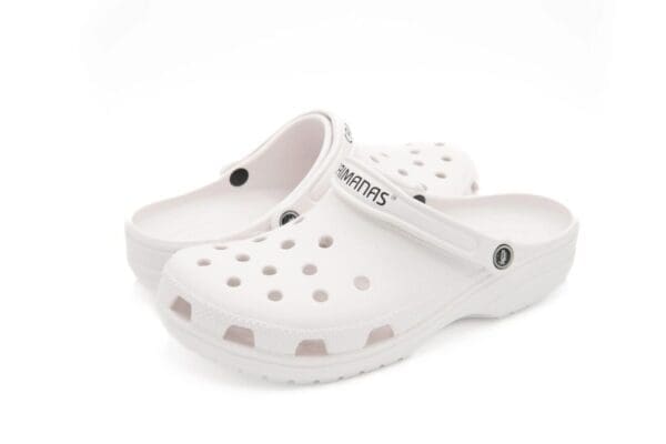 A pair of white crocs with black dots on them.