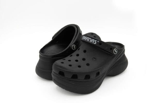 A pair of black crocs on top of a white surface.