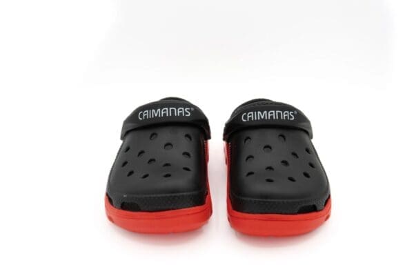 A pair of black and red crocs on top of a white surface.