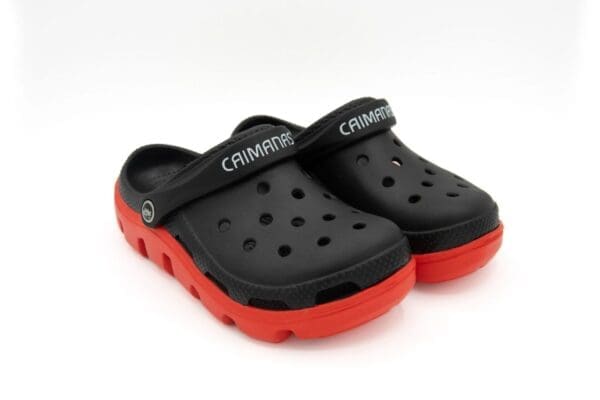 A pair of black and red crocs on top of a white surface.