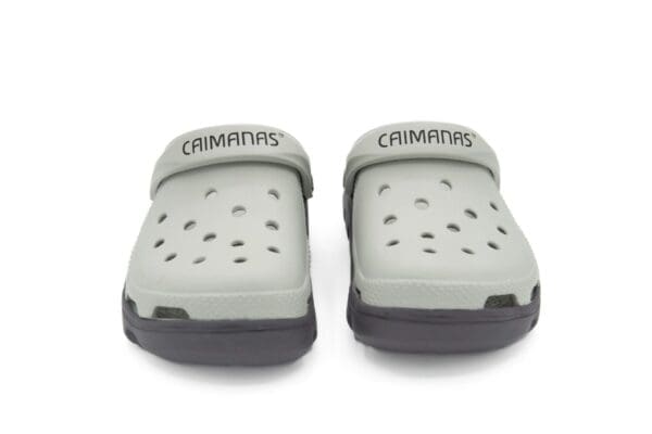 A pair of gray sandals with the word " crimmins " written on them.