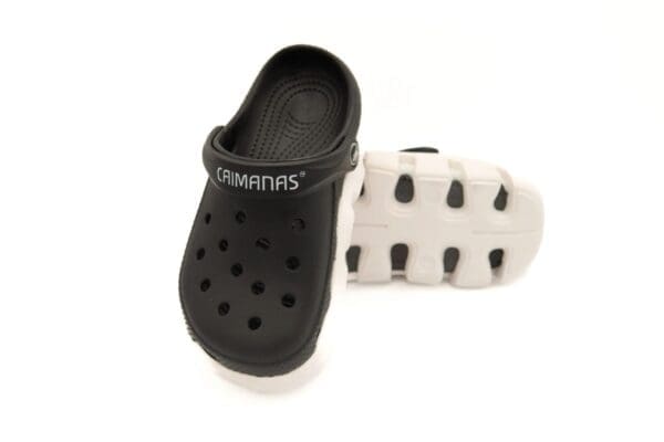 A pair of black and white crocs on top of each other.