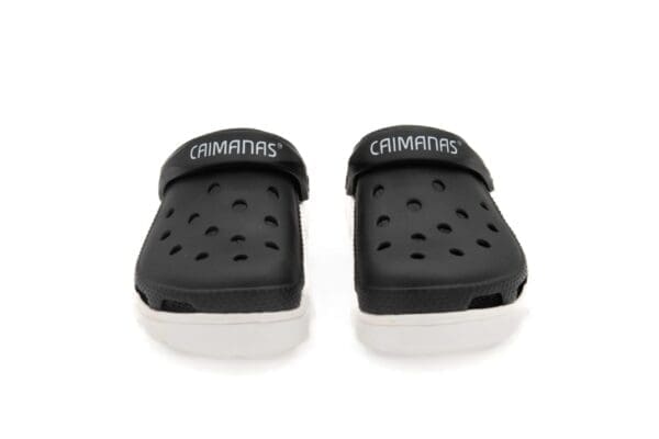 A pair of black and white crocs with the word " champs " written on them.