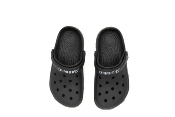 A pair of black crocs with the word columbus written on them.