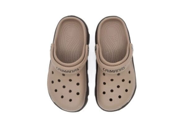 A pair of beige crocs with black dots on them.