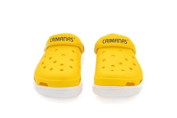 A pair of yellow sandals with the word " camanbas ".