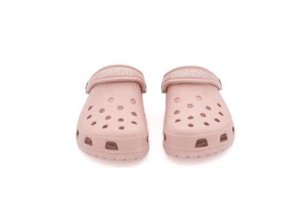 A pair of pink crocs with holes on them.