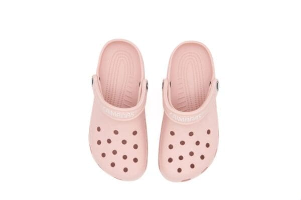 A pair of pink crocs with black dots on them.