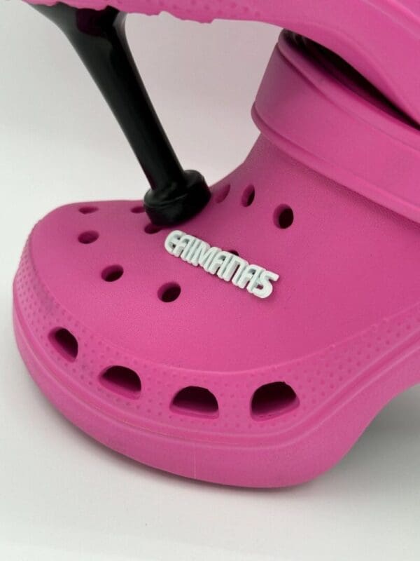 A pink crocs shoe with a black handle.